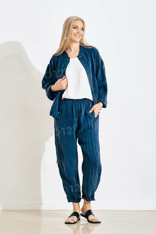 Smiling woman stands in a studio wearing a comfortable outfit, consisting of a matching jacket and pants