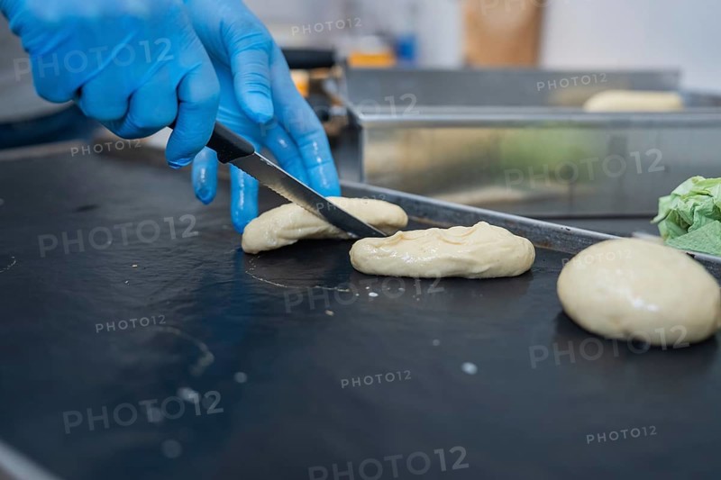 A baker shapes and cuts dough with a knife on a black surface, bake rolls, Haselstaller Hof, Gechingen, Germany