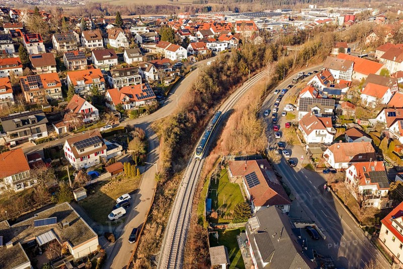 Aerial view of a city with red roofs and a train on rails, test run on the new Hermann-Hesse railway with Siemens Mireo Plus B trains, Calw, Germany
