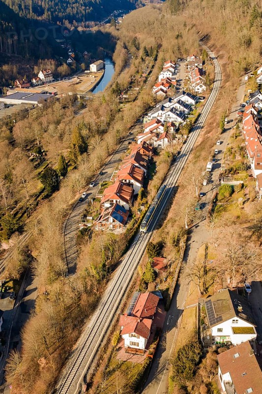 Aerial view of a village with railroad tracks, surrounded by forests and a river, test run on the new Hermann-Hesse railway with Siemens Mireo Plus B trains, Calw, Germany