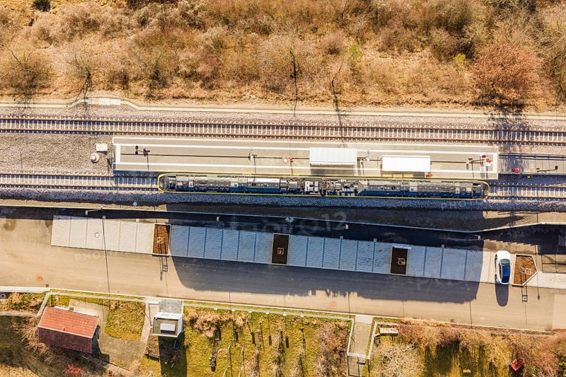 Aerial view of a train station with train tracks surrounded by trees and vegetation, test run on the new Hermann-Hesse railway with Siemens Mireo Plus B trains, Calw, Germany