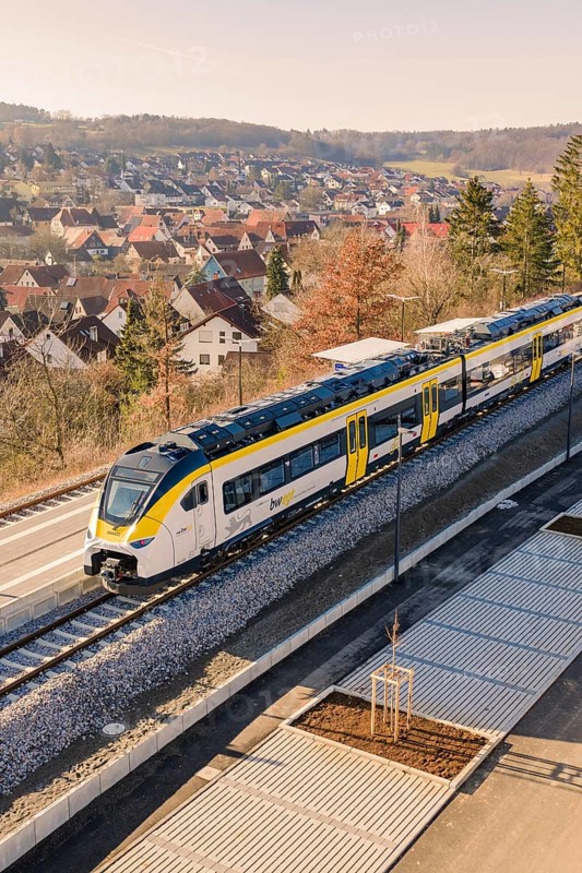 Modern train on rails near a settlement with typical roof houses and nature, test run on the new Hermann-Hesse railway with Siemens Mireo Plus B trains, Calw, Germany