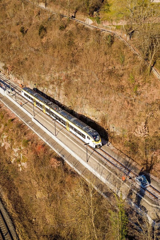 Aerial view of a train traveling through a wooded area surrounded by bare trees, test run on the new Hermann-Hesse railway with Siemens Mireo Plus B trains, Calw, Germany