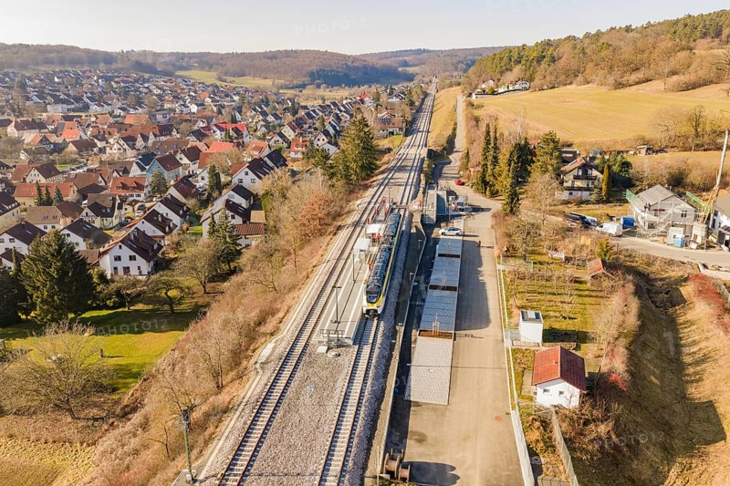 Railway line runs through a village with red-roofed houses, surrounded by trees and meadows, test run on the new Hermann Hesse railway with Siemens Mireo Plus B trains, Calw, Germany