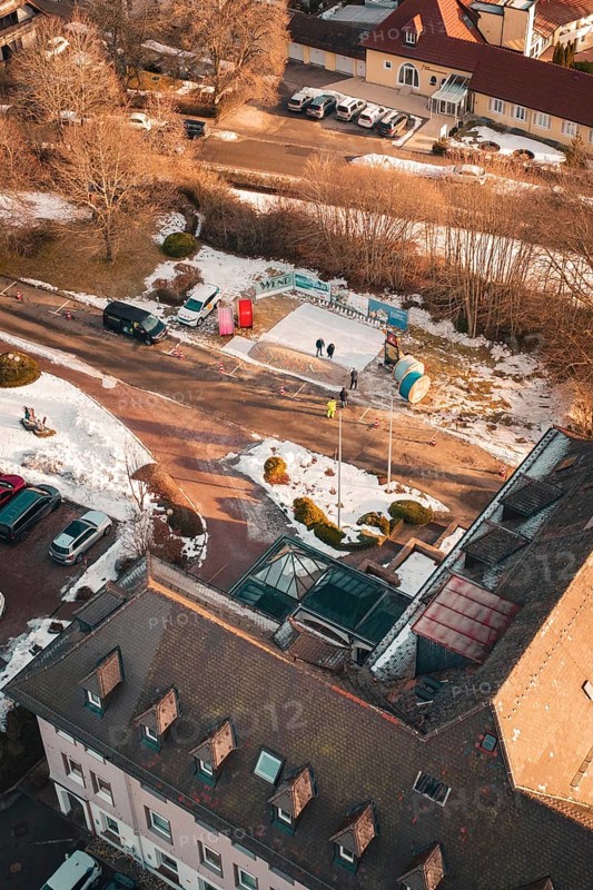 Bird's eye view of a snowy road with buildings and parked cars on a sunny winter day, Freudenstadt, Black Forest, Germany