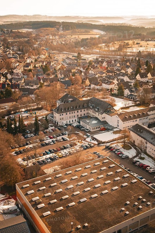 Urban area in winter with snow-covered houses and roads in warm sunlight from a bird's eye view, District Office, Freudenstadt, Black Forest, Germany