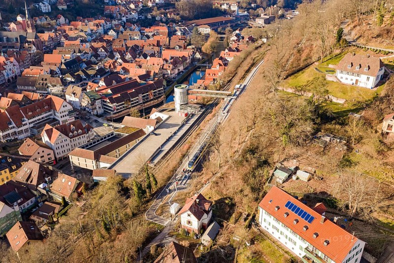 Urban landscape with railway line and river, surrounded by houses from aerial view, test run on the new Hermann-Hesse railway with Siemens Mireo Plus B trains, Calw, Germany