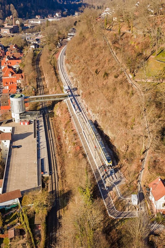 Aerial view of a railway line along a wooded slope with urban surroundings, test run on the new Hermann-Hesse railway with Siemens Mireo Plus B trains, Calw, Germany