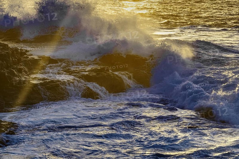 Waves break against rocks in golden sunlight, the spray is illuminated, Playa Blanca/Yaiza Lanzarote