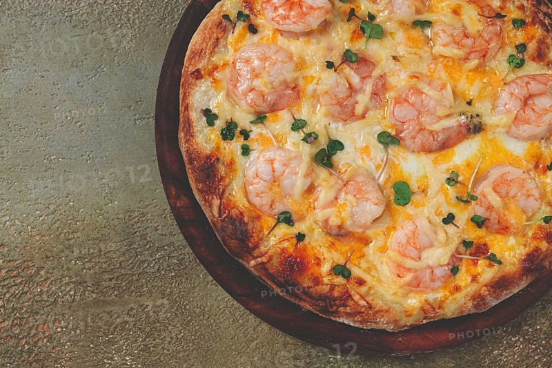 Four cheese pizza with shrimp and fresh microgreens, served on a wooden board, homemade, no people