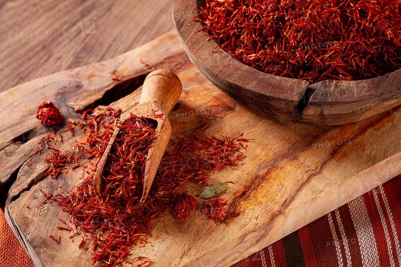 Spice saffron threads, in a wooden bowl, on a wooden table, top view, close-up