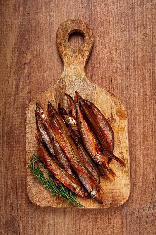 Cold smoked capelin, on a wooden chopping board, no people