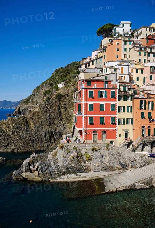 Colourful houses on rocky coast under blue sky, fishing village of Riomaggiore, Cinque Terre, La Spezia province, Liguria, Italy