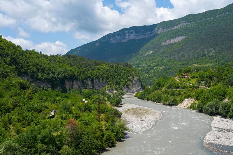 River flows through a wooded valley in the mountains under a cloudy sky, Rioni river near Alpana, Racha-Lechkhumi region and Lower Svaneti, Georgia