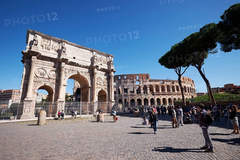 Arch of Constantine and Colosseum surrounded by tourists under blue sky, Rome, Lazio, Italy