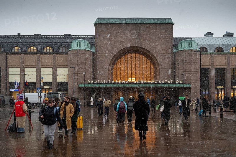 Busy side entrance to Central Station with Christmas decoration during snowfall, Helsinki, Finland