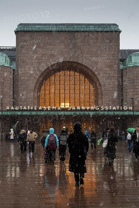 Busy side entrance to Central Station with Christmas decoration during snowfall, Helsinki, Finland