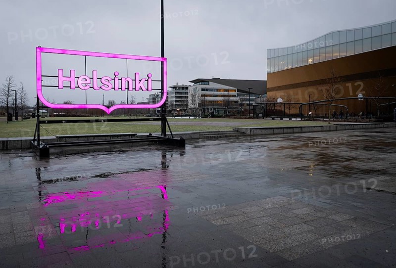 Large pink glowing Helsinki city logo, in front of Oodi Central Library and Cultural Center, designed by ALA Architects, Helsinki, Finland