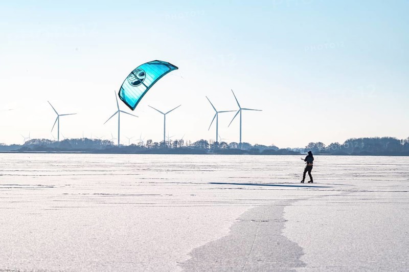 Person kiting on frozen Dümmer Lake, wind turbines in the background, Lembruch, Diepholz district, Lower Saxony, Germany