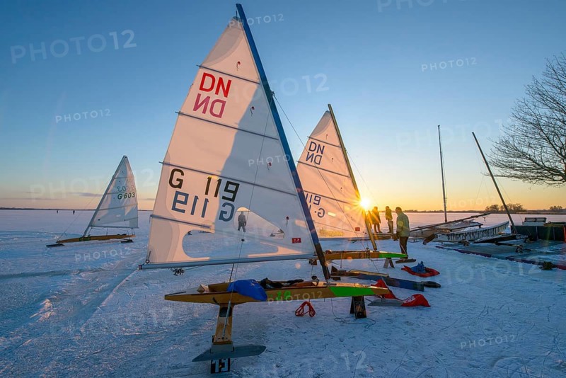 Ice sailboats in evening light and bright sun on the shore of a frozen lake Dümmer, Dümmer See, east shore north of Lembruch, Lembruch, Diepholz district, Lower Saxony, Germany