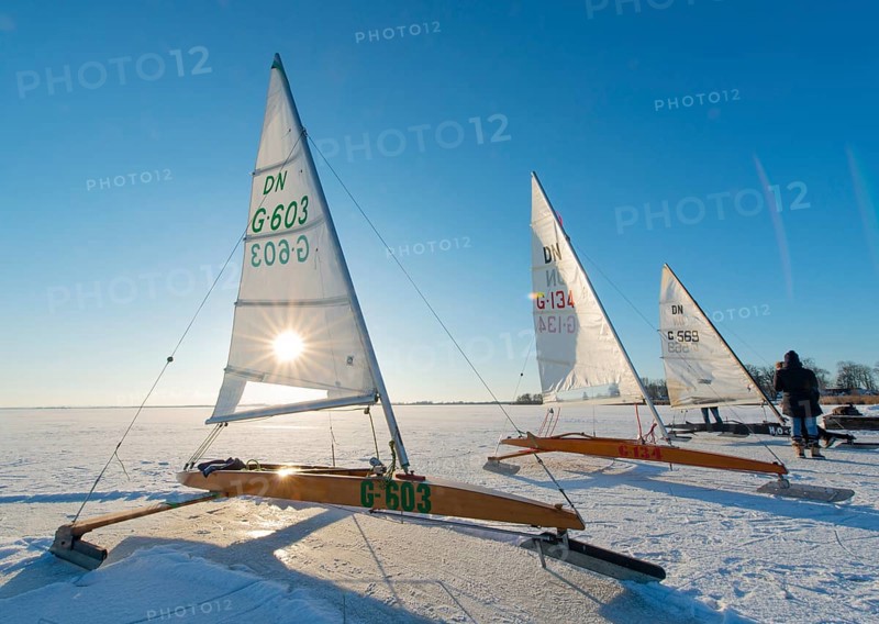 Three ice sailboats on frozen lake under clear blue sky and bright sunshine on frozen Dümmer, Dümmer See, east shore north of Lembruch, Lembruch, Diepholz district, Lower Saxony, Germany
