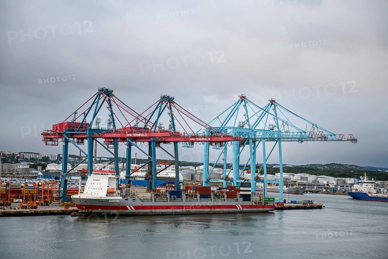 Industrial port with container cranes, container bridges and cargo ship under overcast sky, Gothenburg, Västra Götalands län, Sweden