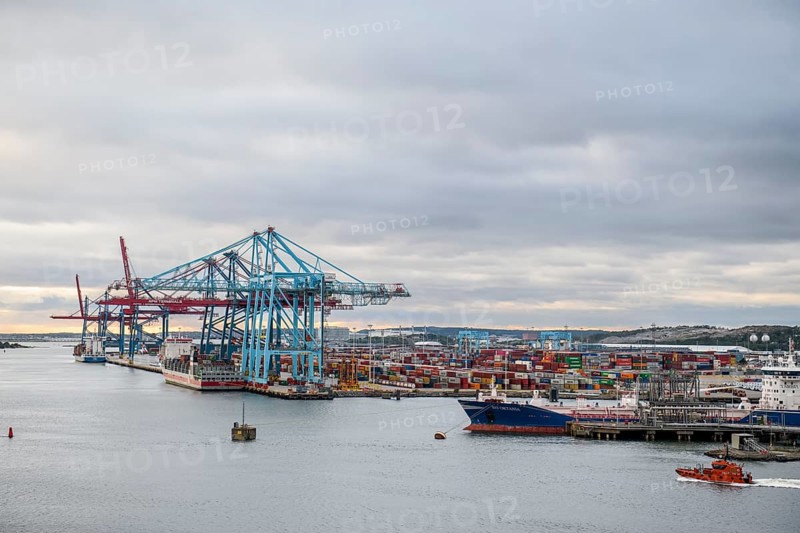 Industrial port with large cranes, container bridges and container ships under a cloudy sky, Gothenburg, Västra Götalands län, Sweden