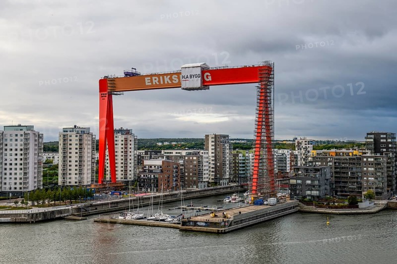 Large orange construction crane in front of modern residential buildings on the site of the former Eriksberg shipyard at the port in Gothenburg, Stena Line Göteborg-Kiel, Gothenburg, Västra Götalands län, Sweden