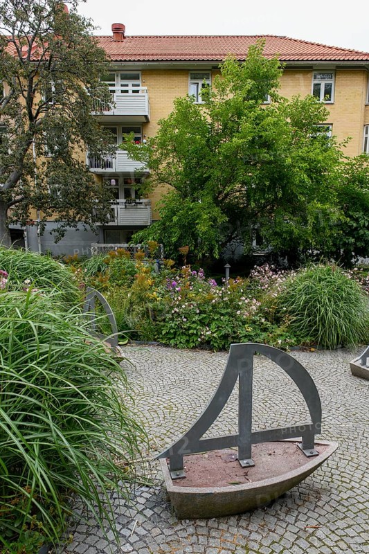 Green garden with art installations and lush plants in front of a residential building, Gothenburg, Västra Götalands län, Sweden