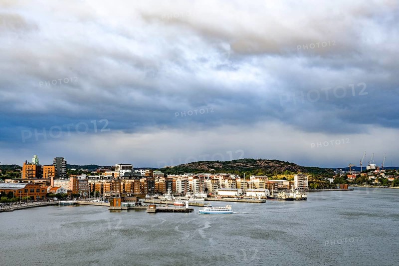 Urban landscape with waterside buildings and hills in the background under cloudy sky, Gothenburg Harbour, Göteborg, Västra Götalands län, Sweden