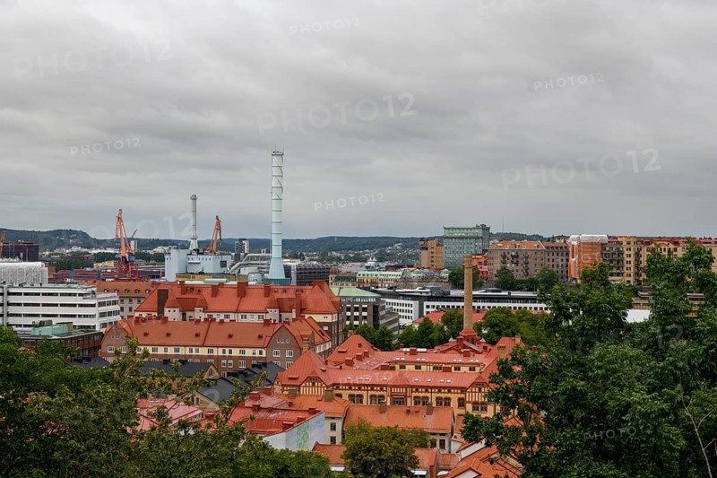 View of an urban landscape from Skansen with industrial elements and red roofs under a cloudy sky, Gothenburg, Västra Götalands län, Sweden