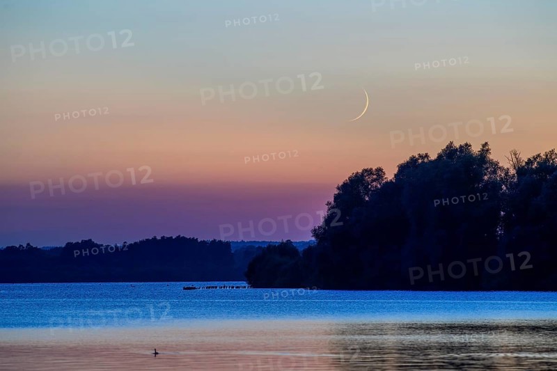 Delicate crescent moon over quiet Dümmer Lake late in the evening at sunset, Lembruch, Dümmer See, Lower Saxony, Germany