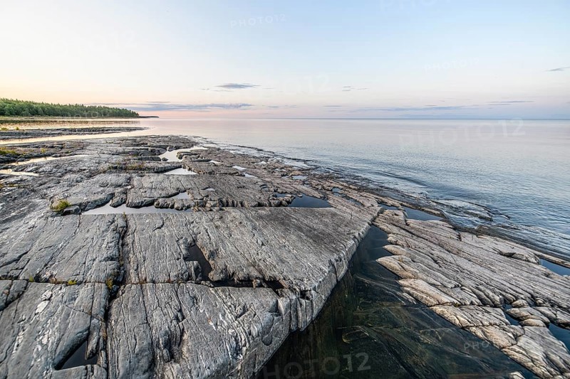 Far-reaching view of the quiet lake Vänern with gently sloping granite rocks archipelago under calm clear sky in the evening, Värmlands län, Sweden