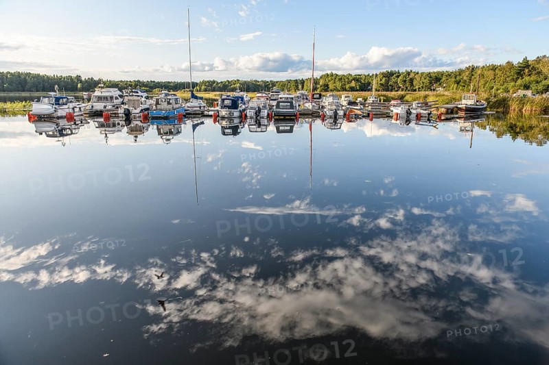 Several boats are moored in the quiet sports boat harbor of Ekenäs, water reflects the sky and the pleasure boats, Ekenäs, Värmlandsnäs peninsula, Värmlands län, Sweden