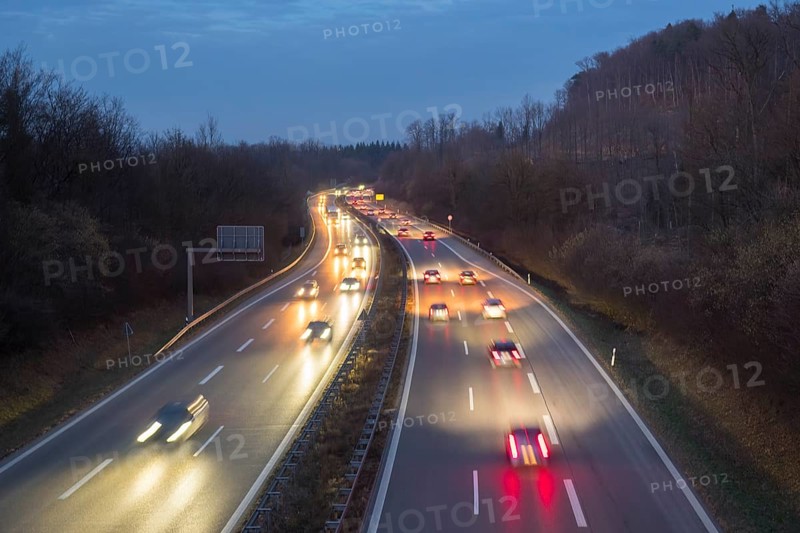 Night view of a motorway with fast moving cars and lights, surrounded by forest, near Stuttgart, Baden-Württemberg, Germany