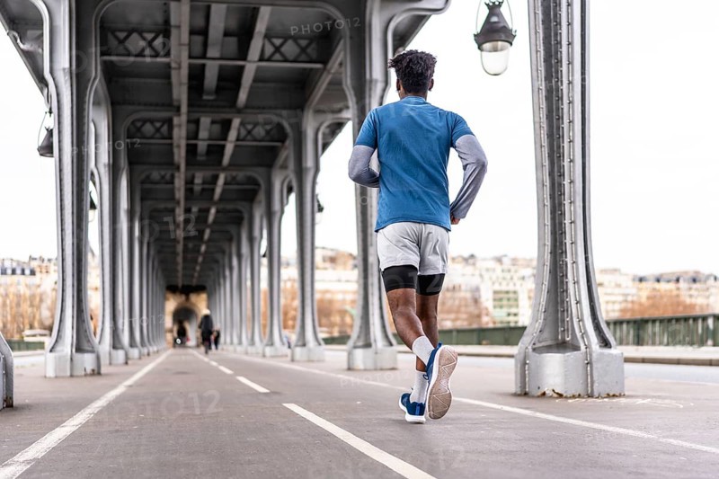Young black man running on the bir hakeim bridge in paris, exercising in the modern urban environment of the city, focusing on health, wellness, and an active lifestyle