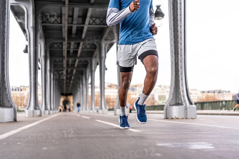 Young man running a daily urban workout across bir hakeim bridge in paris, showcasing fitness, determination and healthy city living against iconic architecture