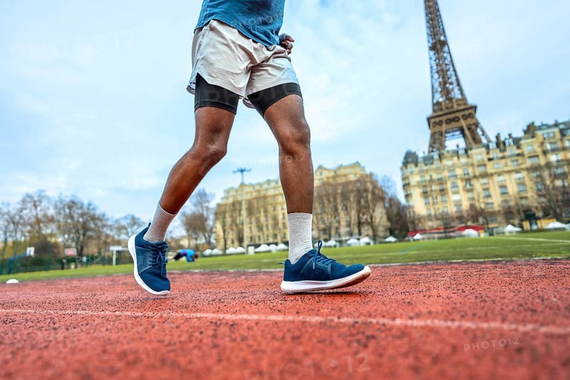 Athlete running on a red track with the iconic eiffel tower and parisian buildings in the background, combining urban landscape with fitness and active lifestyle