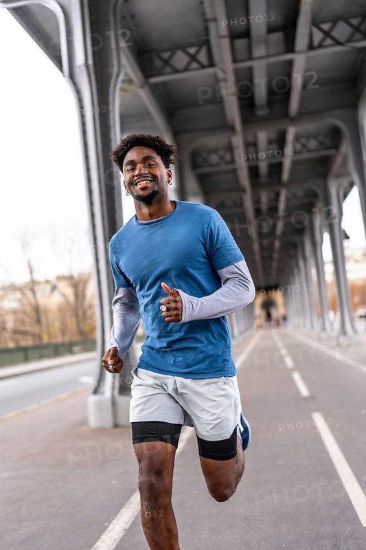 Smiling black man jogging on pariss bir hakeim bridge, staying fit and active in casual sportswear while enjoying urban training, energy and a healthy lifestyle outdoors