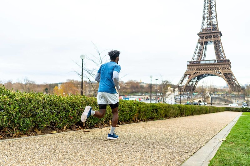 Man actively running along a path in paris, maintaining his fitness and enjoying urban sports with the iconic eiffel tower prominently featured in the background under a cloudy sky