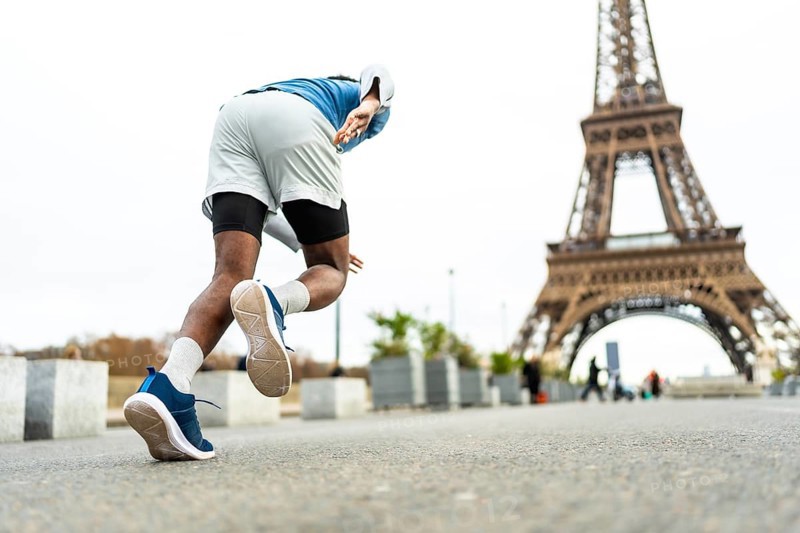 Male athlete starting to run in paris, training near the eiffel tower, symbolizing endurance, wellness, and an active lifestyle in a famous urban setting
