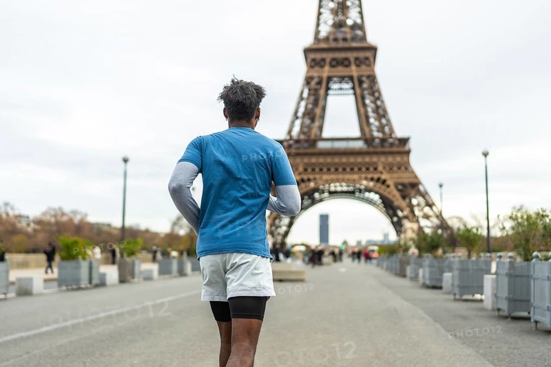 Person jogging on a parisian street with the iconic eiffel tower in the background, promoting urban fitness, healthy lifestyle, and exploring the city while exercising