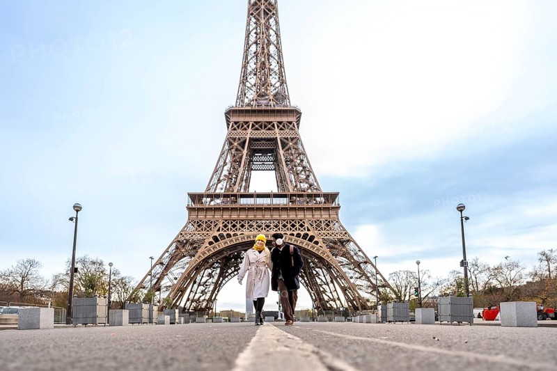 Couple walking hand in hand toward the eiffel tower in paris on a cloudy day, sharing a romantic moment while exploring the city's iconic architecture and sightseeing charms