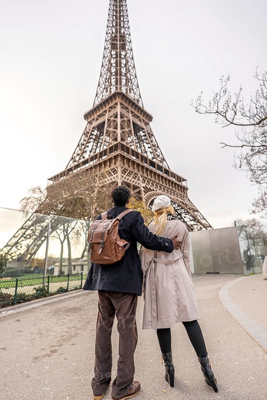 Couple walking together and embracing, looking at the iconic eiffel tower, celebrating travel, romance, and tourism in the beautiful city of paris, france