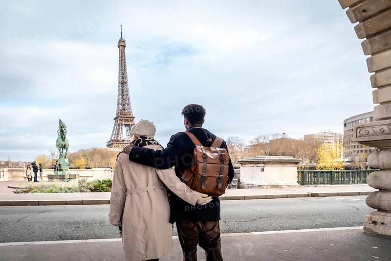 Adult black man and white woman embracing, looking at the iconic eiffel tower and cityscape of paris, enjoying travel and romance during a european vacation