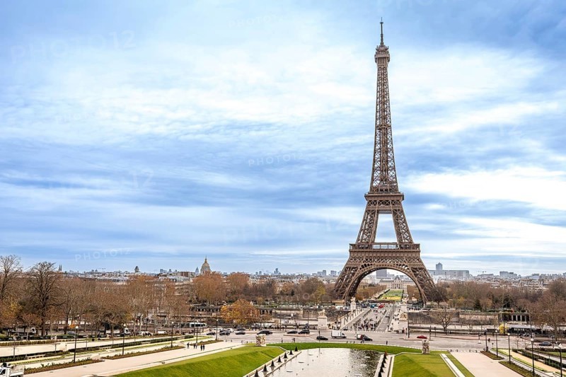 Eiffel tower rising above trocadero gardens, iconic paris skyline and historic monument framed by promenades, trees and a dynamic cloudy sky for travel and tourism use