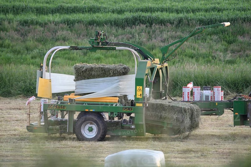 Agricultural machine round baler wraps hay bales in a field, Osnabrücker Land, Lower Saxony, Germany