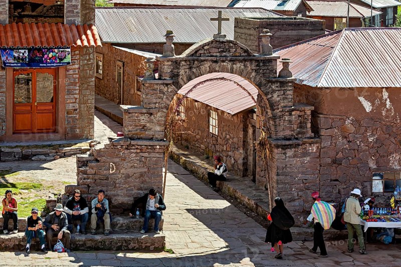 A bustling marketplace in a traditional village with stone walls and arches, The city's large square on Taquile Island in Lake Titicaca in Peru