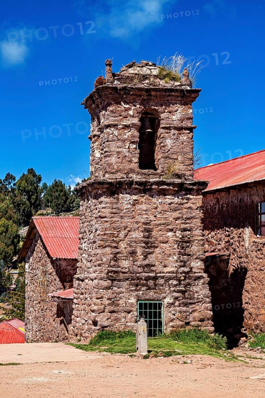 An old stone church with a bell tower and red roofs under a blue sky, The historic church on Taquile Island in Lake Titicaca in Peru