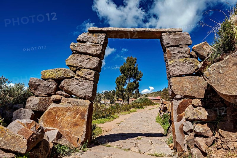 Rectangular stone archway with visible path below, blue sky in the background, stone gates on Taquile Island in Lake Titicaca in Peru